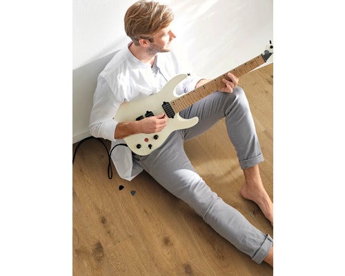 Mann sitzt auf dem Boden und spielt E-Gitarre.