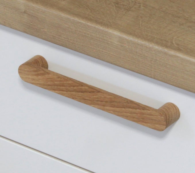 Ein einzelner Möbelgriff aus Holz an einer Schubladenfront