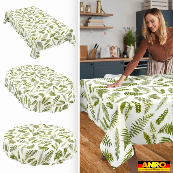 Abwaschbare Tischdecke mit Farn-Muster in rechteckiger, ovaler und runder Form. Frau deckt einen Tisch in einer hellen Küche. ANRO Logo.