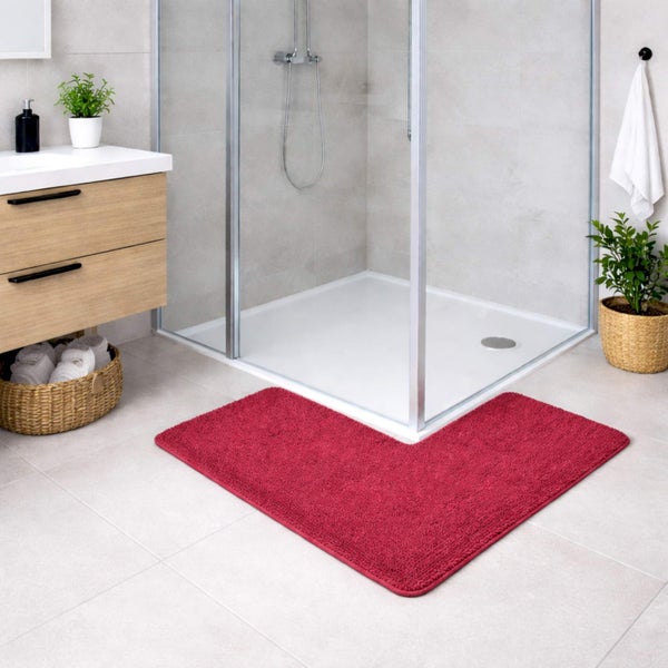 Rote Eck-Badematte in L-Form vor einer Glasdusche in einem modernen Badezimmer mit Waschtisch aus Holz.