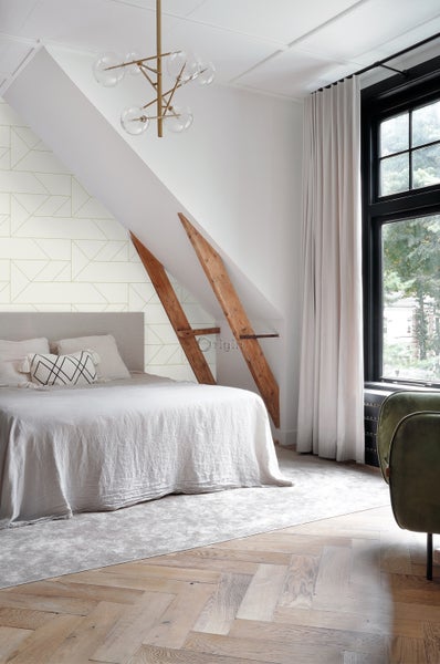 Schlafzimmer mit Bett, Fenster und geometrischer Tapete