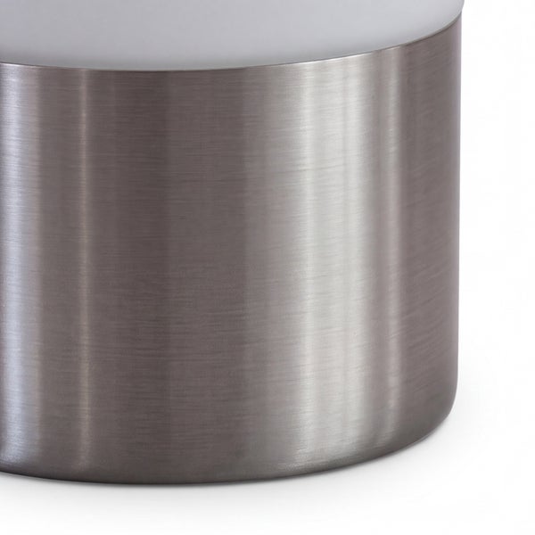 Zylindrische Leuchtenbasis aus gebürstetem Metall mit einem Diffusoraufsatz.