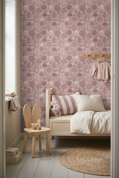 Vliestapete im Kinderzimmer mit Waldmotiv und Tieren, weißes Kinderbett, Hasenstuhl aus Holz und runder Juteteppich.