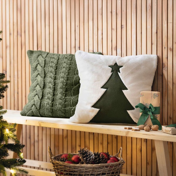 Dekorative Kissen mit Weihnachtsbaum und Zopfmuster auf einer Holzbank