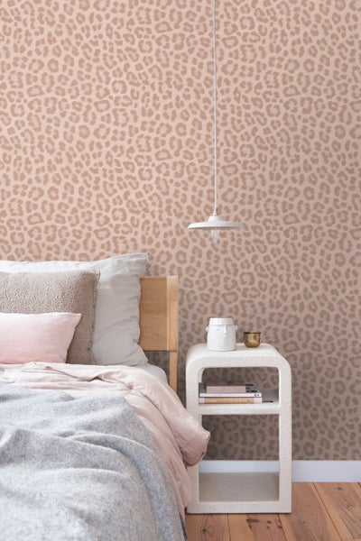 Schlafzimmer mit Leopard-Muster Tapete, Holzbett, weißem Nachttisch und Hängeleuchte. Helle und organisierte Inneneinrichtung.