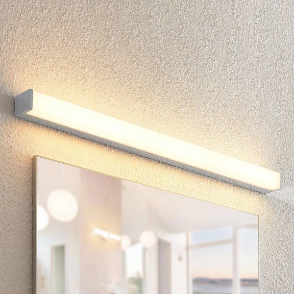 Lineare LED-Wandleuchte über einem Spiegel, Metallgehäuse mit weißem Diffusor, warmweiße Lichtabstrahlung auf strukturierter Wand.