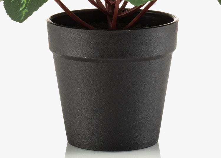 Schwarzer Kunststoff-Blumentopf mit einer künstlichen Pflanze.