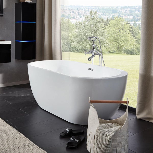 Freistehende Badewanne in modernem Badezimmer vor großem Fenster mit Blick in den Garten und nostalgischer Wannenarmatur.
