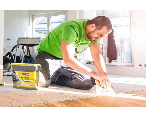 Mann verlegt Parkett mit Soudal Parkettkleber