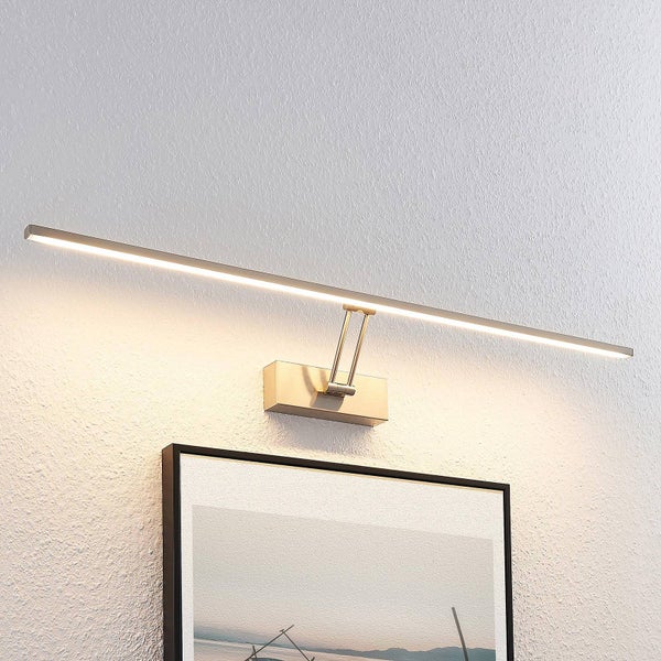 Moderne, längliche LED-Bilderleuchte aus Metall, montiert über einem gerahmten Bild an einer strukturierten Wand.