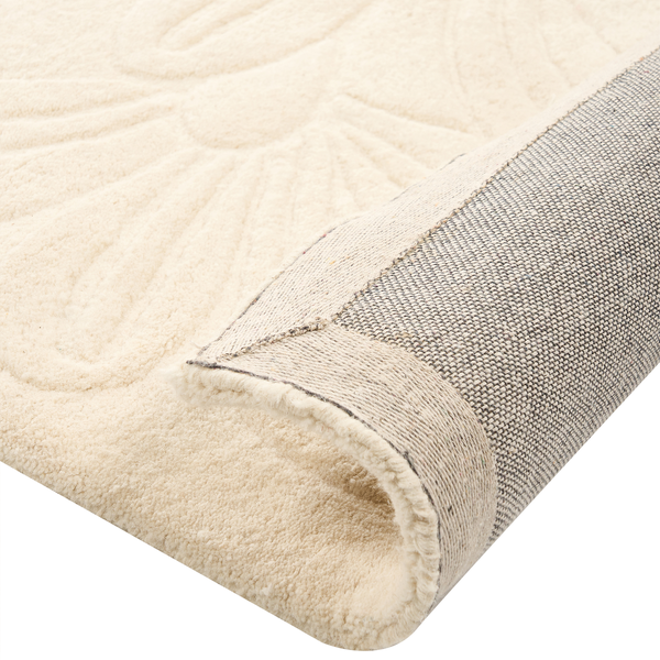 Moderner, heller Wohnraum mit cremefarbenem Teppich mit Blumenrelief auf Parkettboden neben einem braunen Sofa und einer Stehlampe.