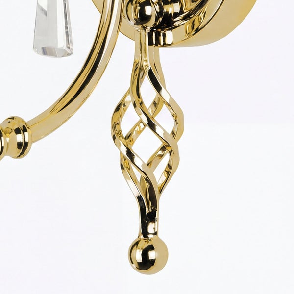 Detailaufnahme einer goldenen Wandleuchte mit Kristallanhänger und dekorativem Metallelement