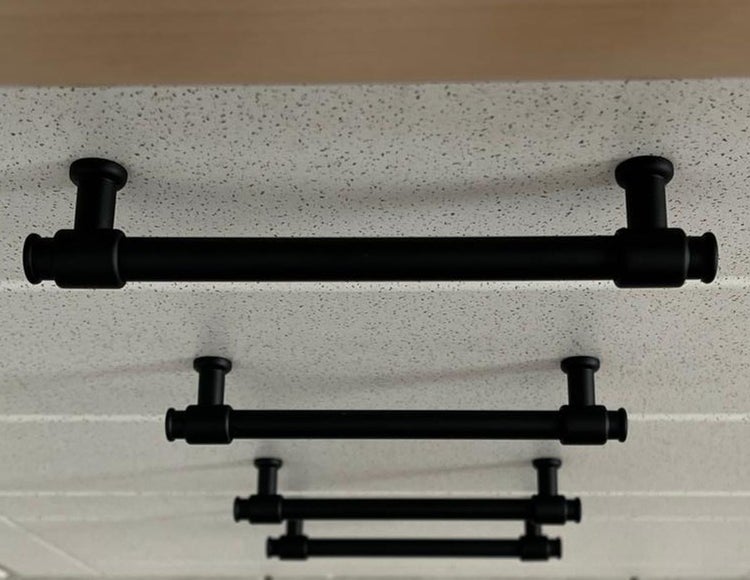 Mehrere schwarze Möbelgriffe an einer weißen Oberfläche