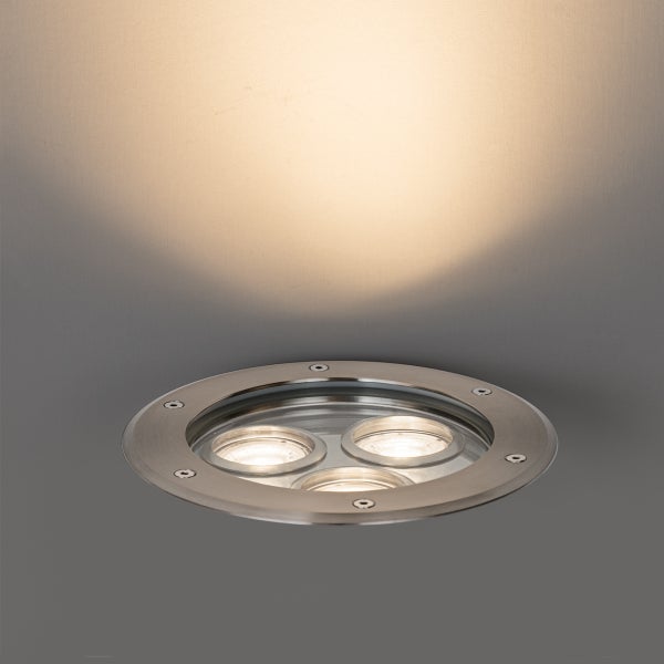 Bodeneinbaustrahler rund aus Edelstahl mit drei LED Lichtquellen und warmweißem Lichtkegel nach oben.