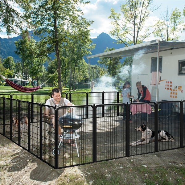 Schwarzes Hundezaun-Set umgibt eine Familie beim Grillen im Freien, mit einem Wohnwagen im Hintergrund.