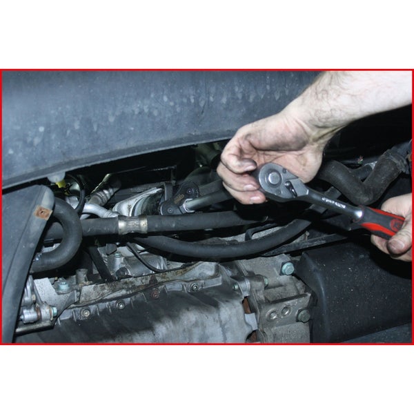 Ein Mechaniker benutzt einen Steckschlüsselsatz an einem Automotor.