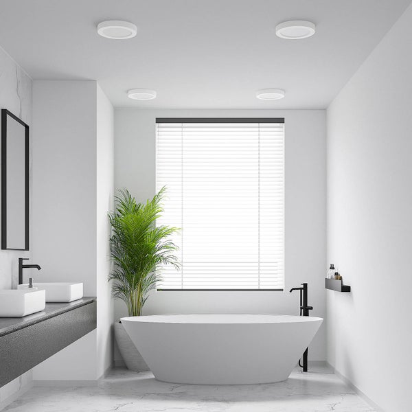 Modernes, helles Badezimmer mit vier runden LED-Einbaustrahlern an der Decke, einer freistehenden Badewanne und weißen Jalousien.