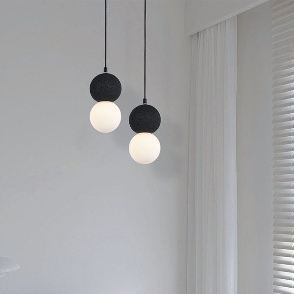 Zwei moderne Pendelleuchten mit kugelförmigen Lampenschirmen aus Stein und Glas
