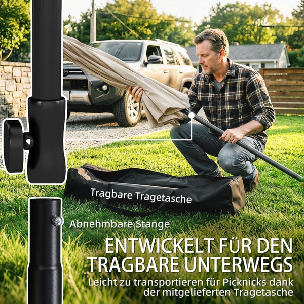 Ein Mann baut einen tragbaren Sonnenschirm mit abnehmbarer Stange im Garten auf, neben ihm liegt eine schwarze Tragetasche auf dem Rasen.