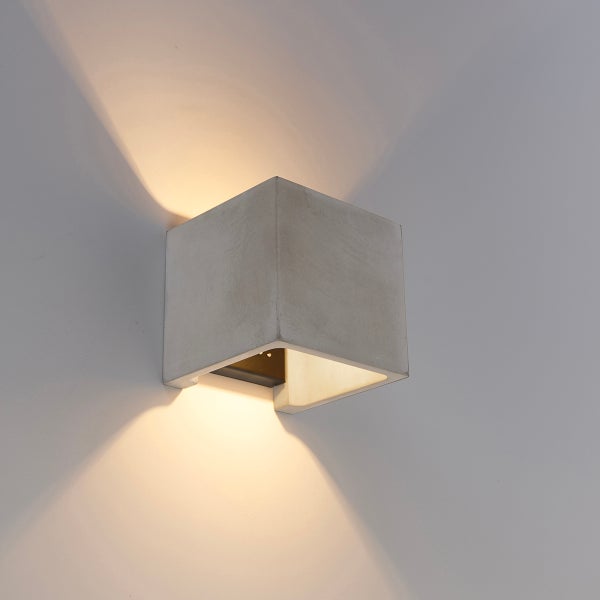 Würfelförmige Wandleuchte aus Beton mit Lichtaustritt nach oben und unten.