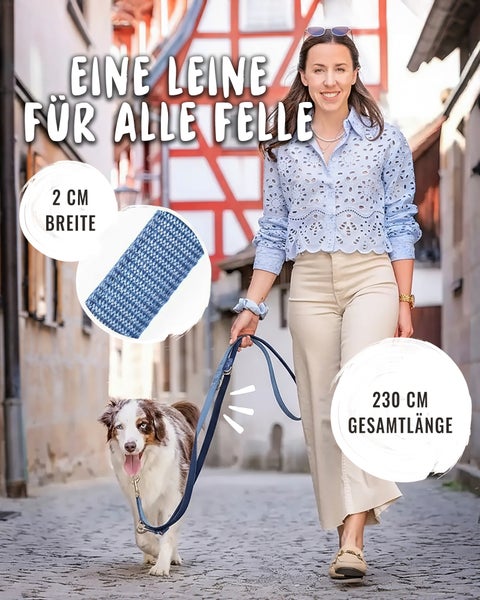 Frau führt Hund an blauer, geflochtener Hundeleine mit 2 Zentimeter Breite und 230 Zentimeter Gesamtlänge in einer hellen Gasse.