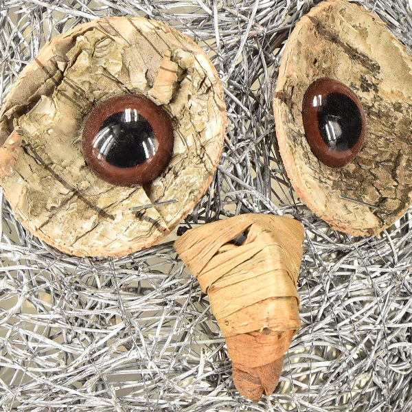 Dekorative Eule aus Naturmaterialien auf silberfarbenem Drahtgeflecht