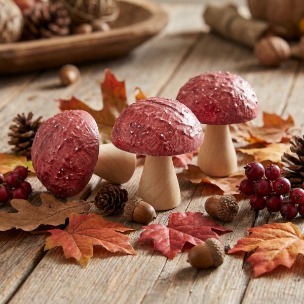 Deko Pilze aus Holz auf rustikalem Holztisch mit herbstlicher Dekoration aus Blättern, Tannenzapfen, Beeren und Eicheln als Tischdeko.