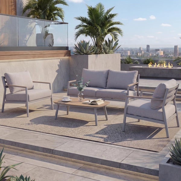Moderne Lounge-Garnitur auf einer hellen Dachterrasse mit einem Zweisitzer-Sofa, zwei Sesseln und einem Couchtisch aus Holz auf einem Teppich.