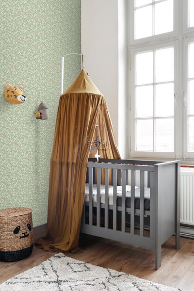 Kinderzimmer mit floraler Tapete, Babybett mit Baldachin und Dekorationen an der Wand