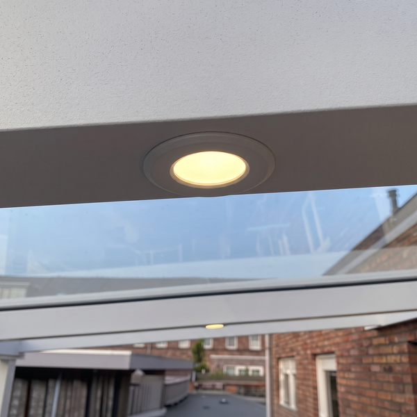 Eingebauter runder LED Einbaustrahler in einer Überdachung mit warmweißem Lichtschein