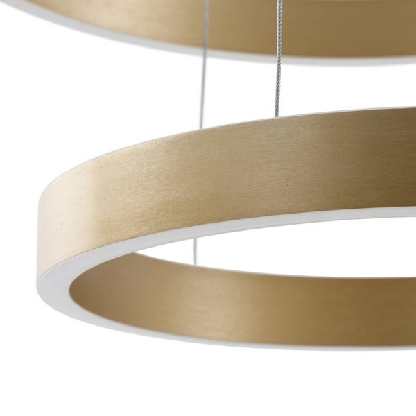 Nahaufnahme einer ringförmigen Pendelleuchte mit goldener gebürsteter Oberfläche und weißem Diffusor an dünnen Drahtseilen.