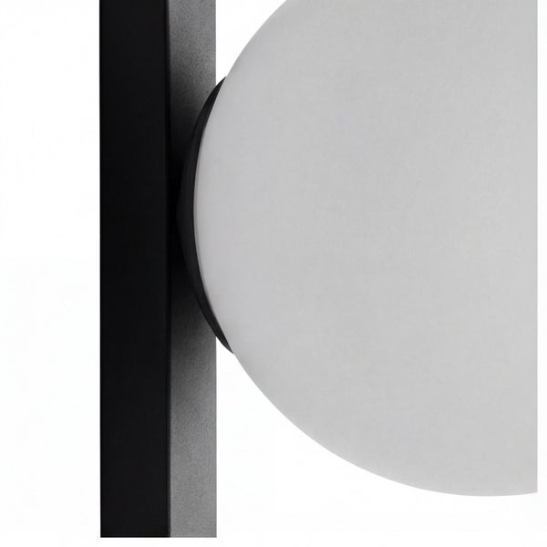 Detail einer modernen Lampe mit weißem kugelförmigem Glasschirm an einem schwarzen Metallrahmen.