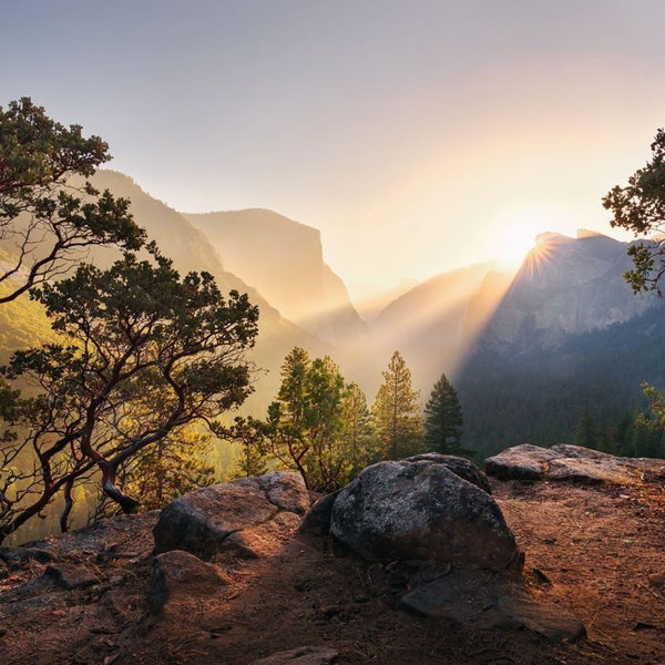 Landschaft mit Bergen, Bäumen und Sonnenaufgang