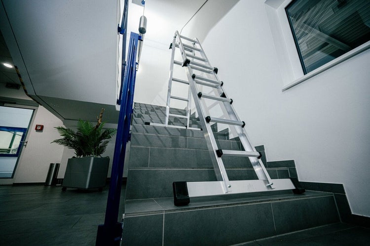 Mehrzweckleiter aus Aluminium auf einer Treppe stehend für sicheres Arbeiten in Innenräumen