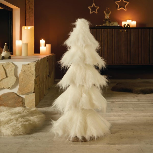 Dekorativer Weihnachtsbaum aus Kunstfell für ein gemütliches Ambiente in einem Wohnraum mit Kamin und Kerzenschein.