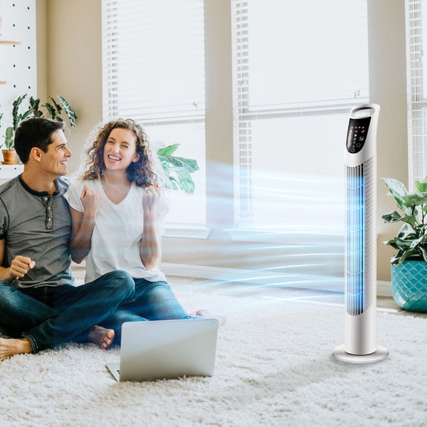 Weißer Turmventilator in hellem Wohnzimmer mit einem Paar auf einem Teppich und einem Laptop, zeigt visualisierten Luftstrom.