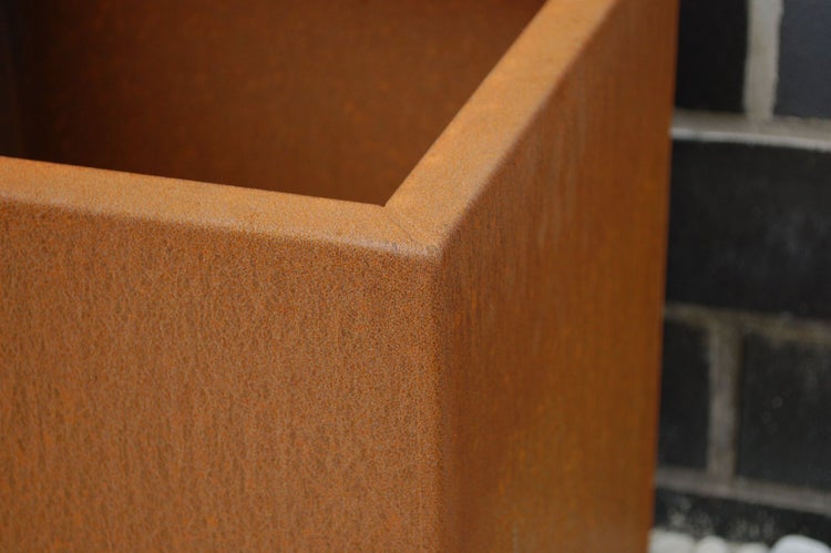Detailaufnahme der Ecke eines Pflanzkübels aus Cortenstahl mit Rosteffekt.