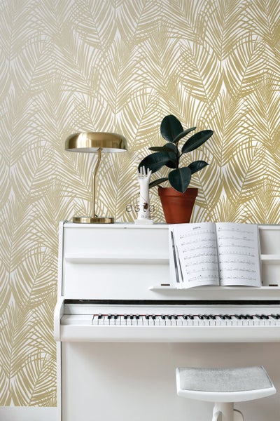 Szene mit einem weißen Klavier, einer goldenen Lampe, einer Zimmerpflanze und einer Tapete mit Blattmuster