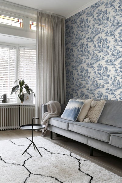 Wohnzimmer mit Sofa, Kissen, Teppich und gemusterter Tapete