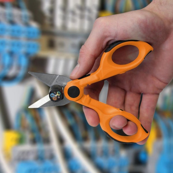 Hand hält eine Elektrikerschere beim Schneiden eines mehradrigen Kabels.