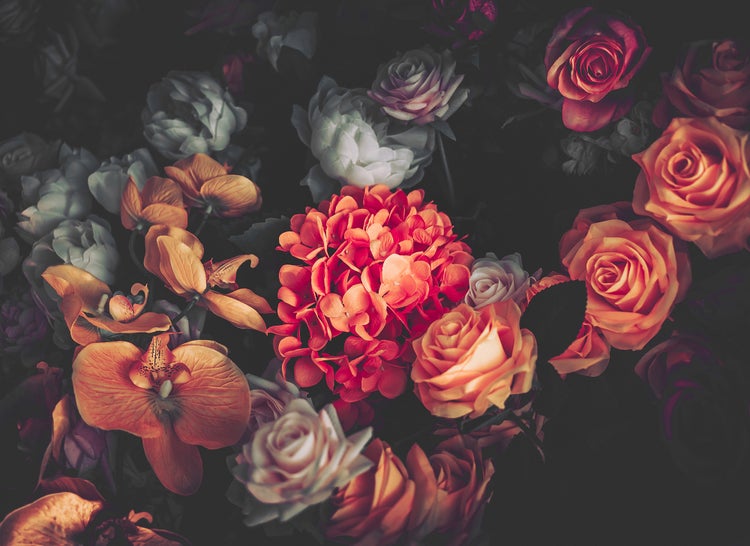 Künstliches Blumengesteck mit Rosen, Orchideen und Hortensien in verschiedenen Farben als Dekoration.