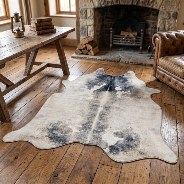 Teppich in Felloptik mit Muster auf Holzboden in rustikalem Wohnzimmer mit Kamin, Holztisch und Ledersessel.