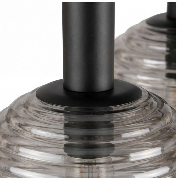 Nahaufnahme einer Leuchte mit rauchgrauem geriffeltem Glasschirm und schwarzem Metallstab.