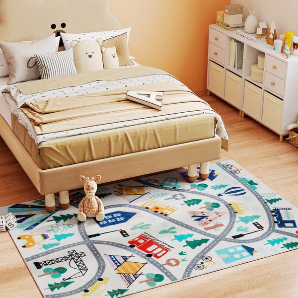 Kinderteppich mit Straßen-Design in einem hellen Kinderzimmer mit Holzbett, weißem Regal und Spielzeug. Der Teppich zeigt Häuser, Bäume und Fahrzeuge.