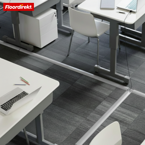 Weiße Kabelbrücke auf grauem Teppichboden in einem hellen Büro mit Schreibtischen für geordnetes Kabelmanagement. Floordirekt Logo.