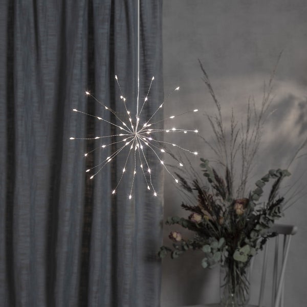 Sternförmige LED-Hängeleuchte im Innenraum, mit Blumenarrangement