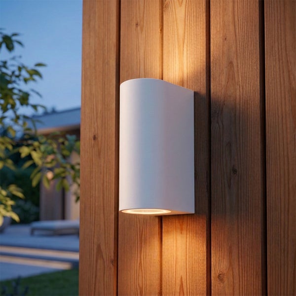 Moderne weiße Außenwandleuchte mit Lichtaustritt nach oben und unten montiert an einer Holzfassade im Garten.