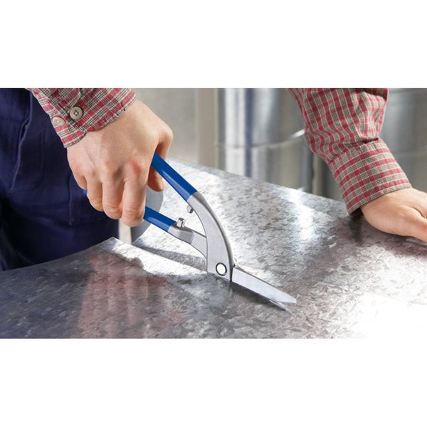 Eine Person schneidet mit einer Blechschere mit blauen Griffen ein verzinktes Metallblech in einer hellen Werkstatt.