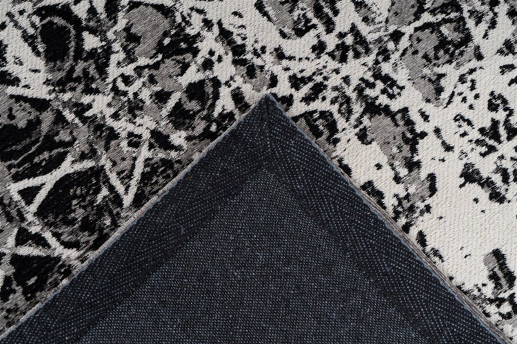 Nahaufnahme eines Teppichs mit abstraktem Muster in Schwarz, Weiß und Grau sowie rutschfester Unterseite.