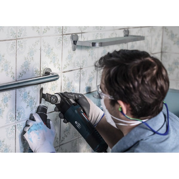 Handwerker demontiert Handtuchhalter mit einem Multifunktionswerkzeug im Badezimmer.